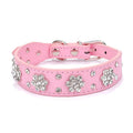A pink PU leather dog collar studded with silver rhinestone flowers and a metal D-ring.
