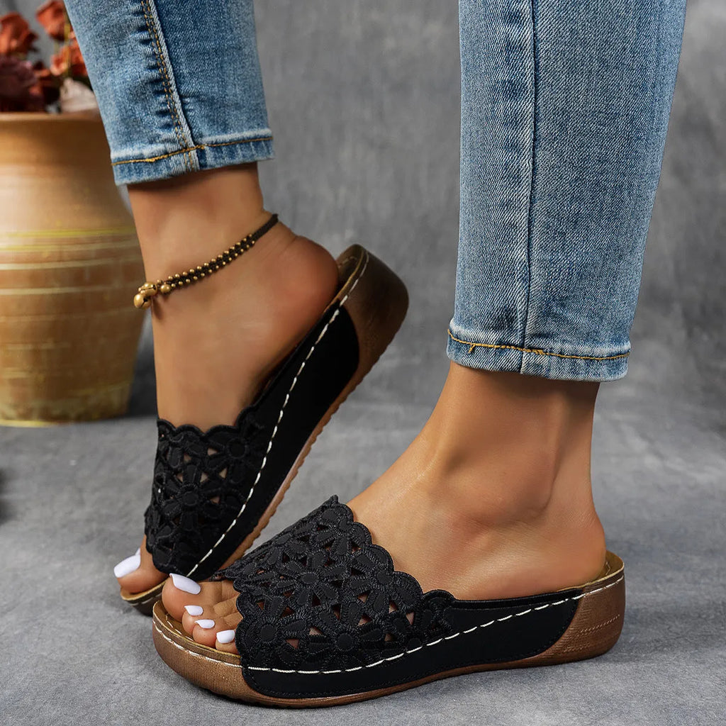 Women's wedge heel beach slippers with flower cutout design on black PVC upper.