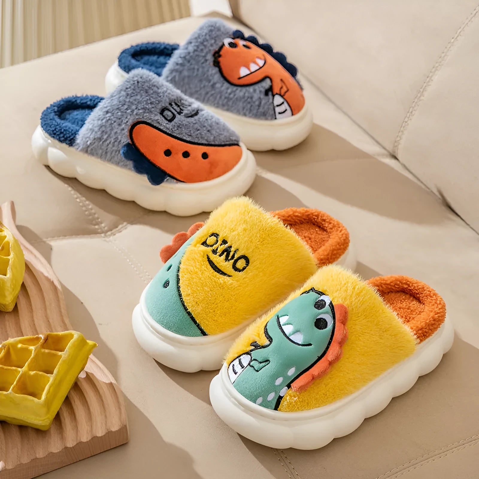 Cotton plush dinosaur print couple slippers in gray, coffee, and orange colours on a white background.