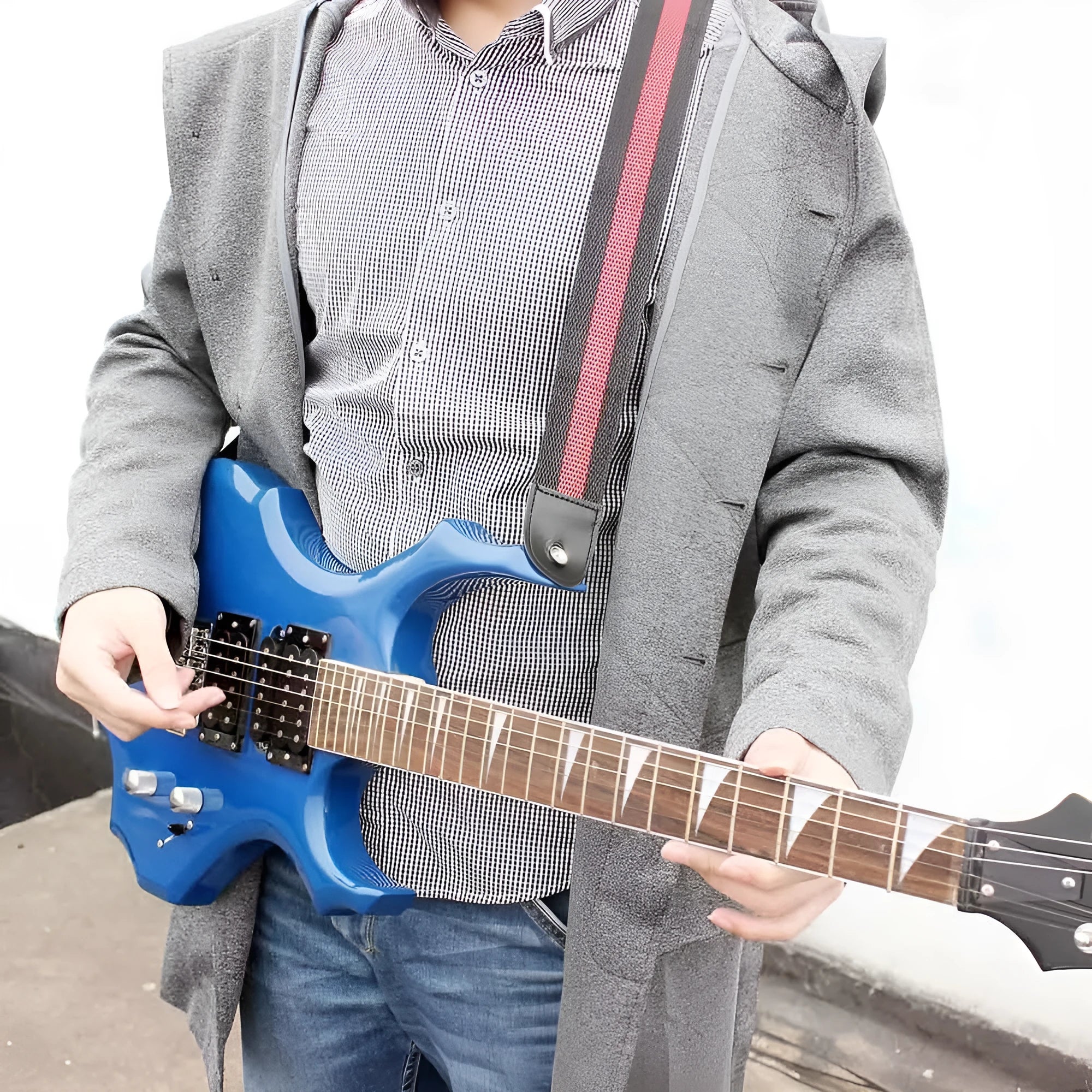 A woven crossbody guitar strap with a stripe pattern, shown attached to an electric guitar.