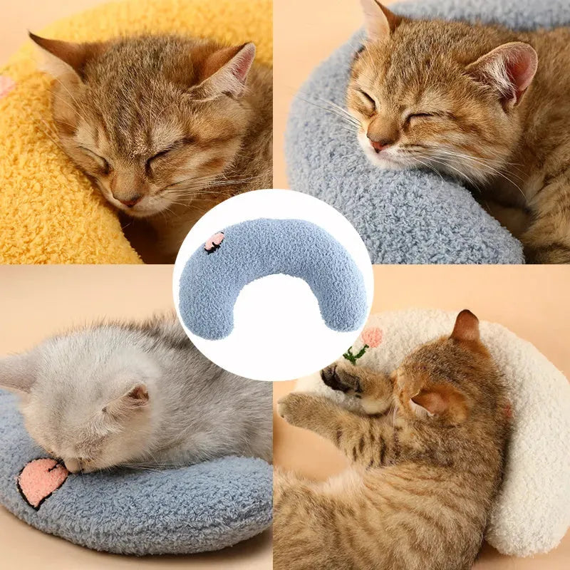 Small white blue yellow U-shaped plush pillow for cats and small dogs on a bed.
