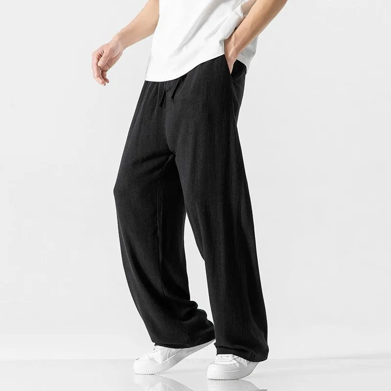 Men's beige loose-fit linen-style bamboo fibre trousers with a cropped leg and drawstring waist laid flat.