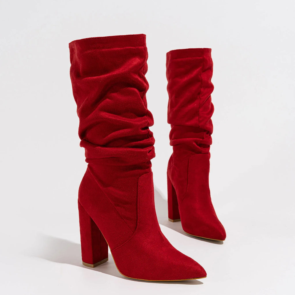 Women's black suede high heel boots with a chunky heel and pointed toe, shown on a model.