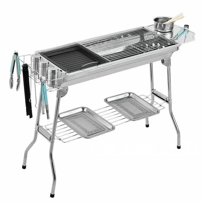 Large stainless steel folding barbecue grill set up for outdoor cooking.