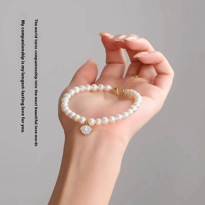 Women's freshwater pearl bracelet with fan-shaped design on wrist, showing elastic and chain fastening options.