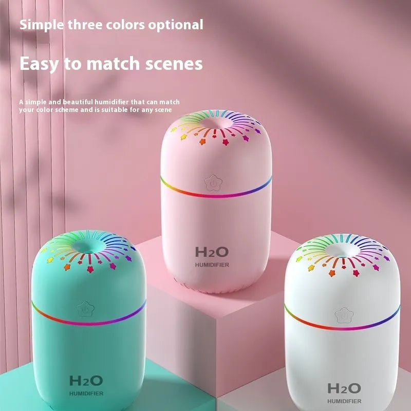 White USB mini humidifier with water tank on desk next to laptop