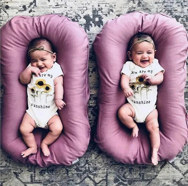 Beige portable baby nest crib cushion measuring 75cm by 45cm on a neutral background
