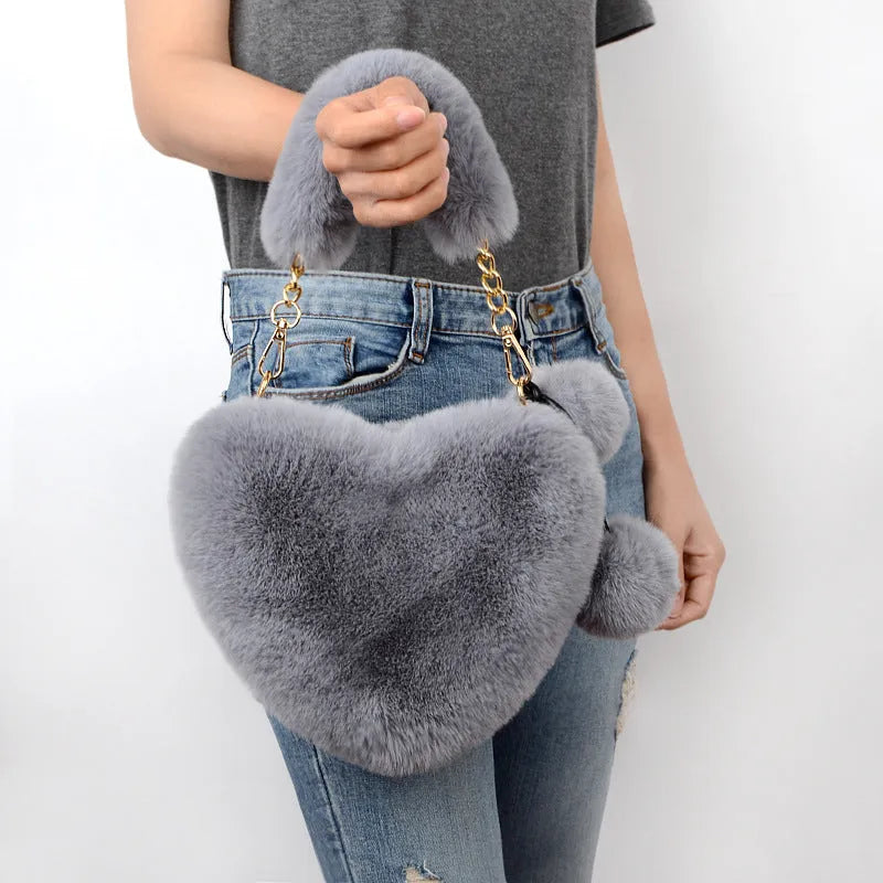 Soft plush heart-shaped women's handbag in a solid colour with a detachable shoulder strap.