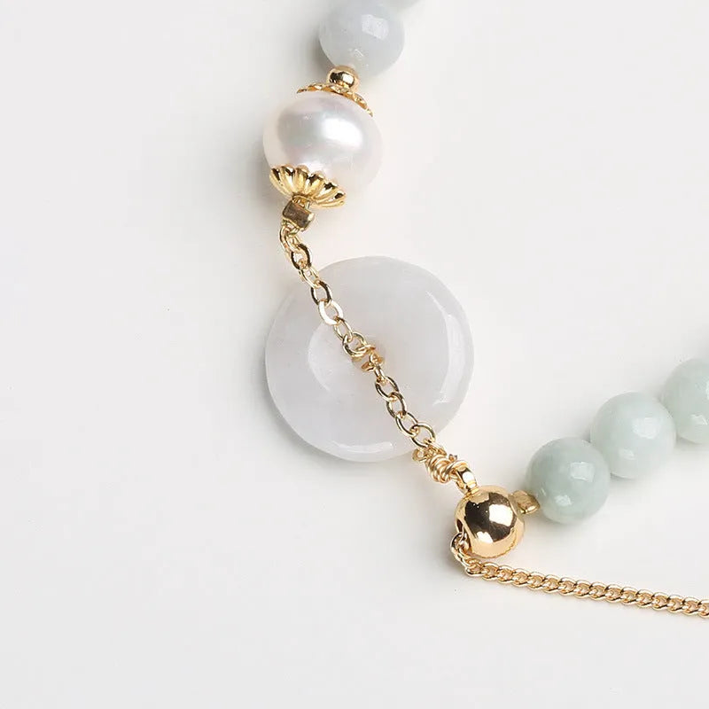 Natural emerald green jade round pendant on a women's bracelet with a geometric peace buckle.