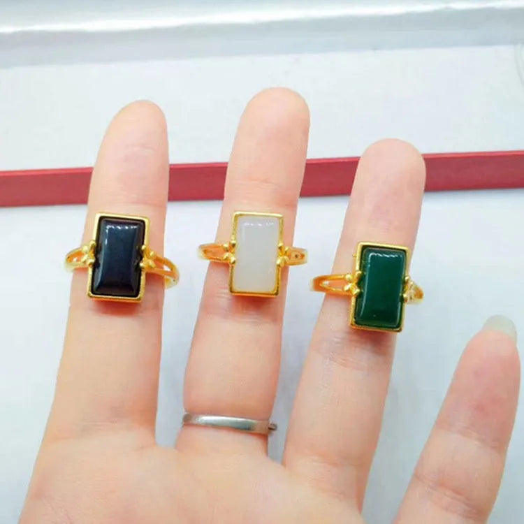 Gold-plated adjustable brass ring with a central inlaid gemstone, shown in black, green, and white colour options.