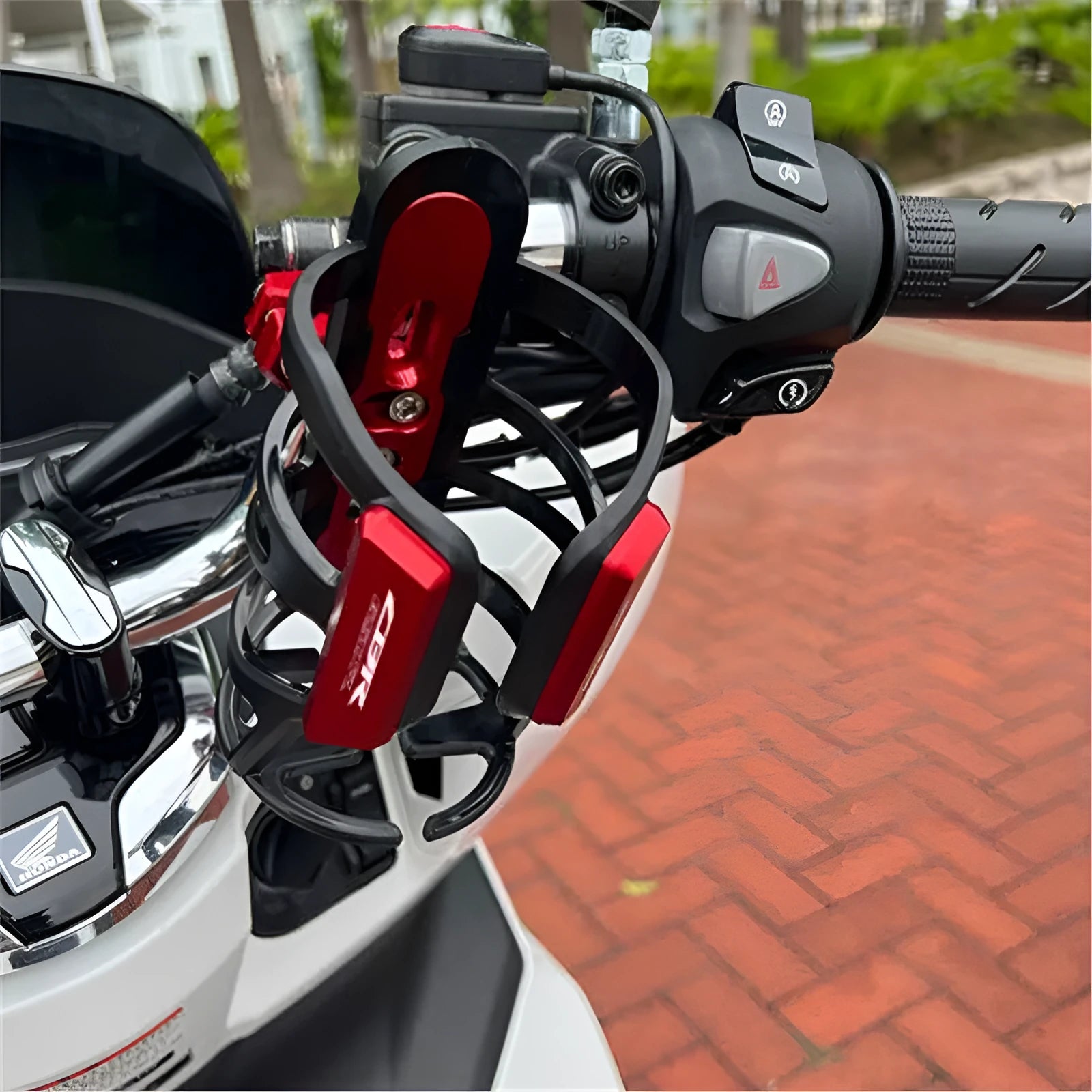 Black modified water bottle cage mounted on a Honda X-ADV scooter bumper for drink storage.