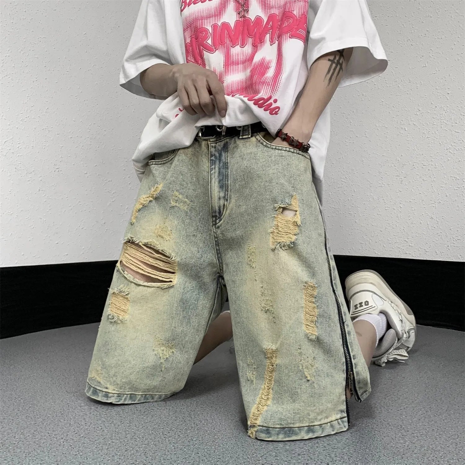 Men's blue denim shorts with a yellow mud distressed finish, rips, loose five-point fit, and button cardigan closure.