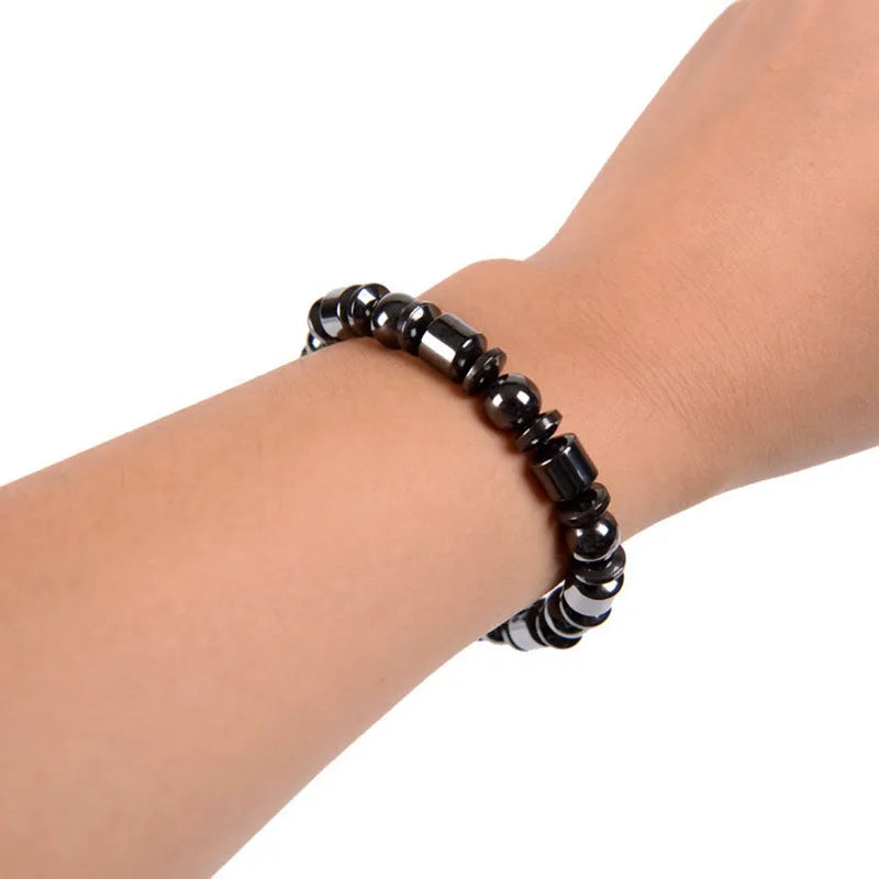 Black pentagram stone magnetic therapy bracelet with stretch fit on a wrist.