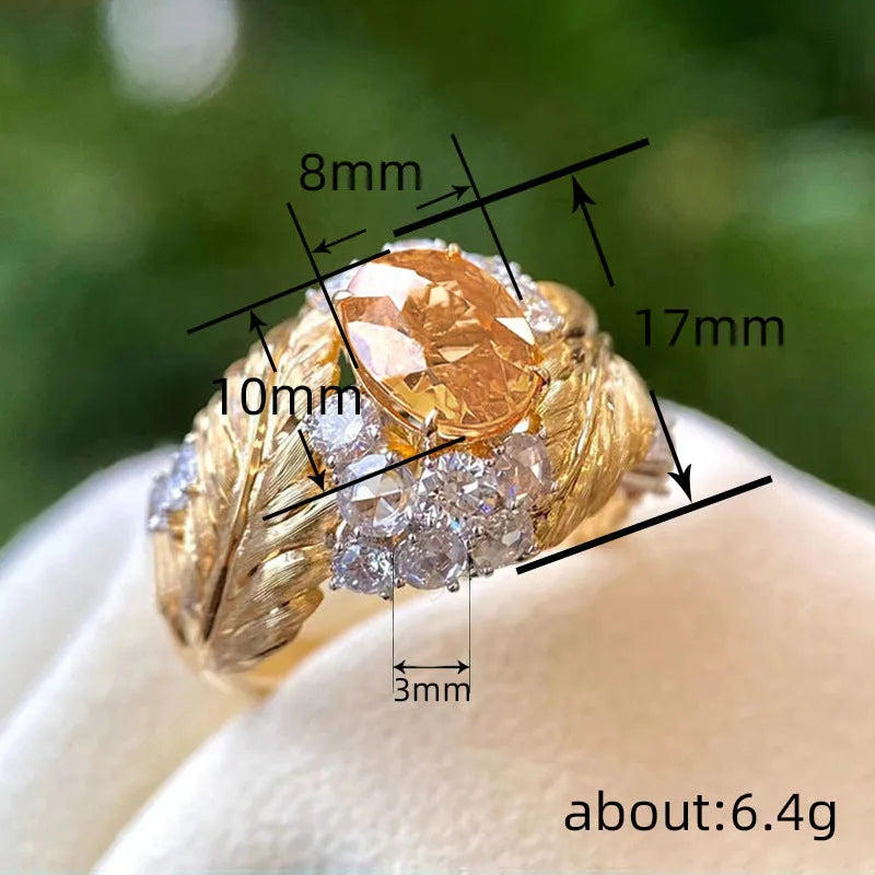 Gold-coloured copper ring with embossed feather pattern and a yellow zircon stone.