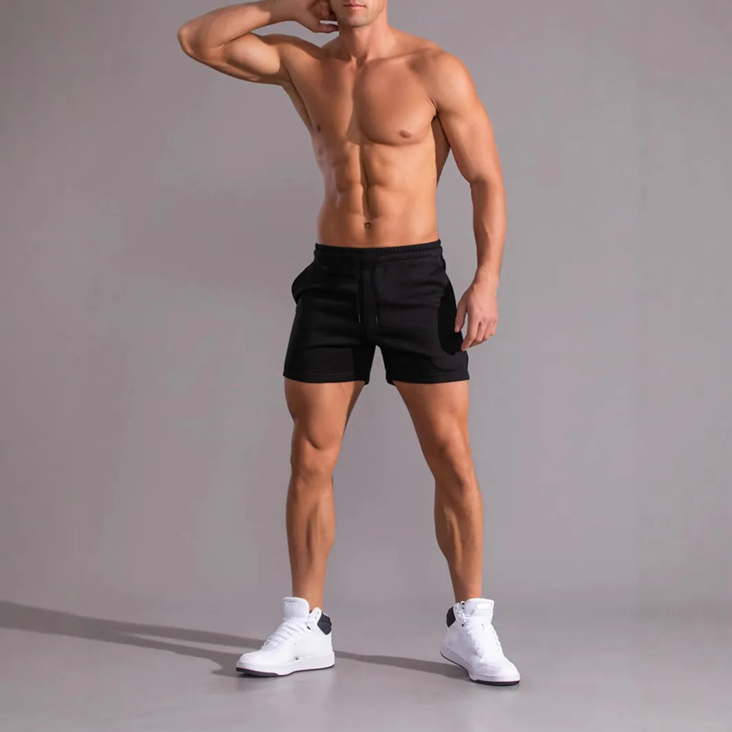 Three pairs of solid colour men's drawstring shorts in black, khaki, and light brown laid flat.