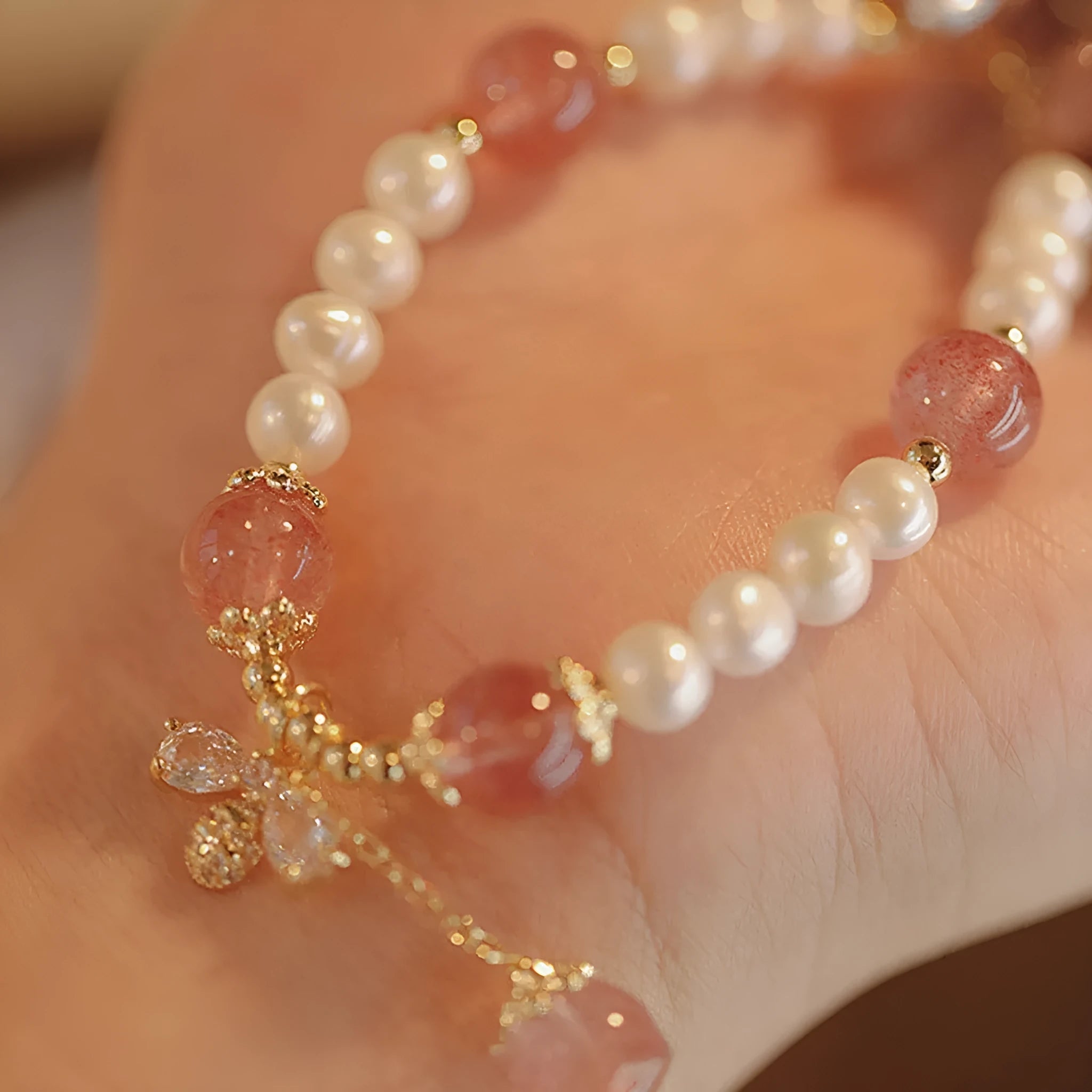 Women's handmade strawberry quartz crystal bracelet with stringed pearls and bow decoration