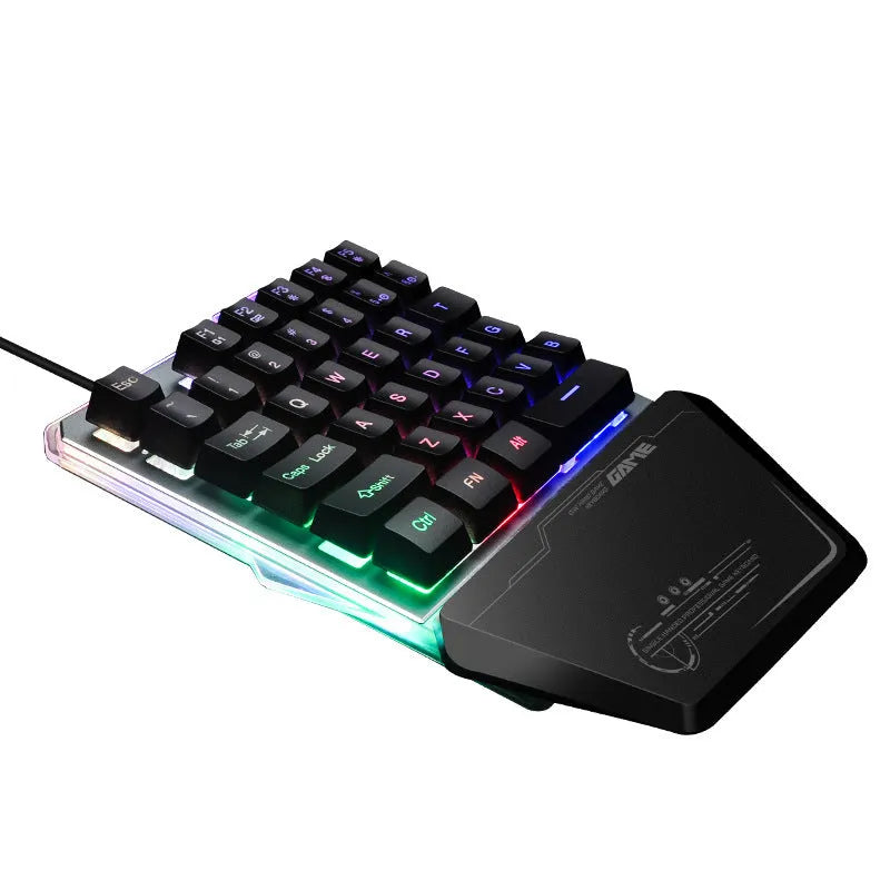 Black one-handed robotic gaming keyboard with RGB backlit keys on a desk.