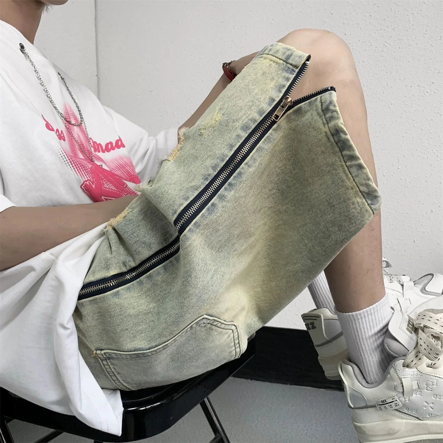 Men's blue denim shorts with a yellow mud distressed finish, rips, loose five-point fit, and button cardigan closure.