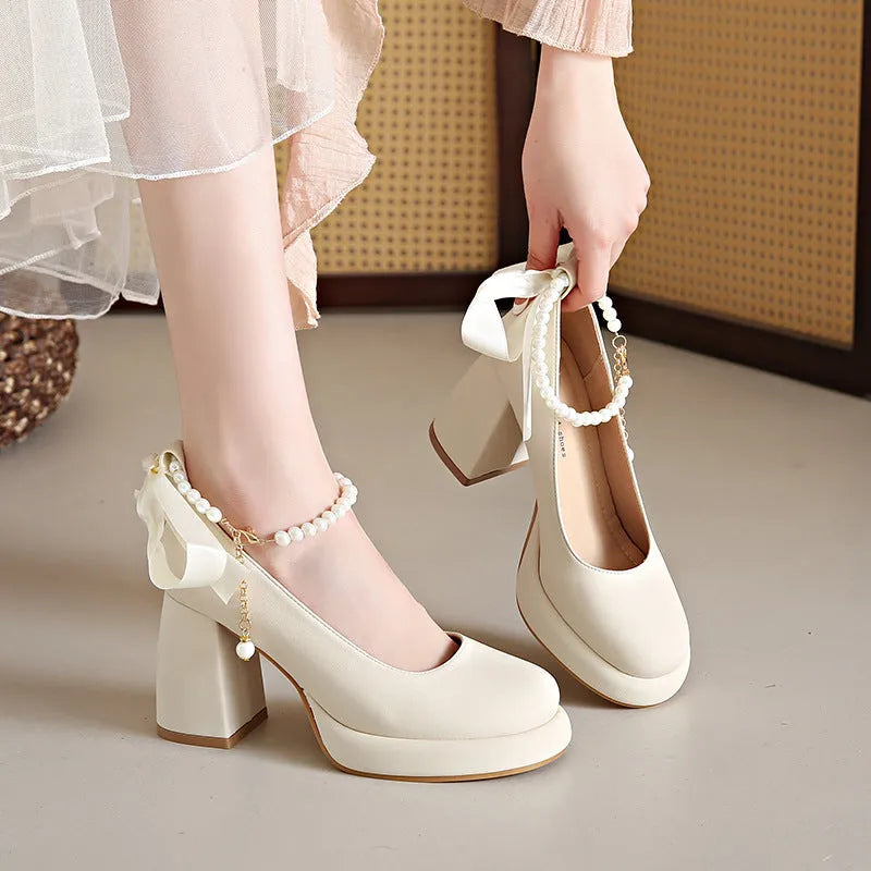 Beige women's Mary Jane shoes with a chunky heel and an ankle-strap buckle on a white background.