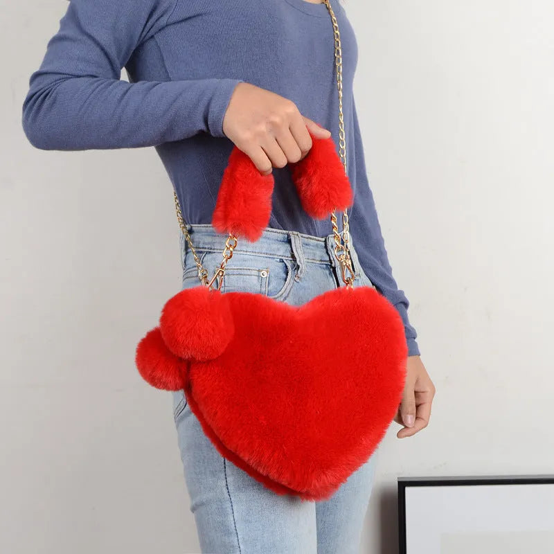 Soft plush heart-shaped women's handbag in a solid colour with a detachable shoulder strap.