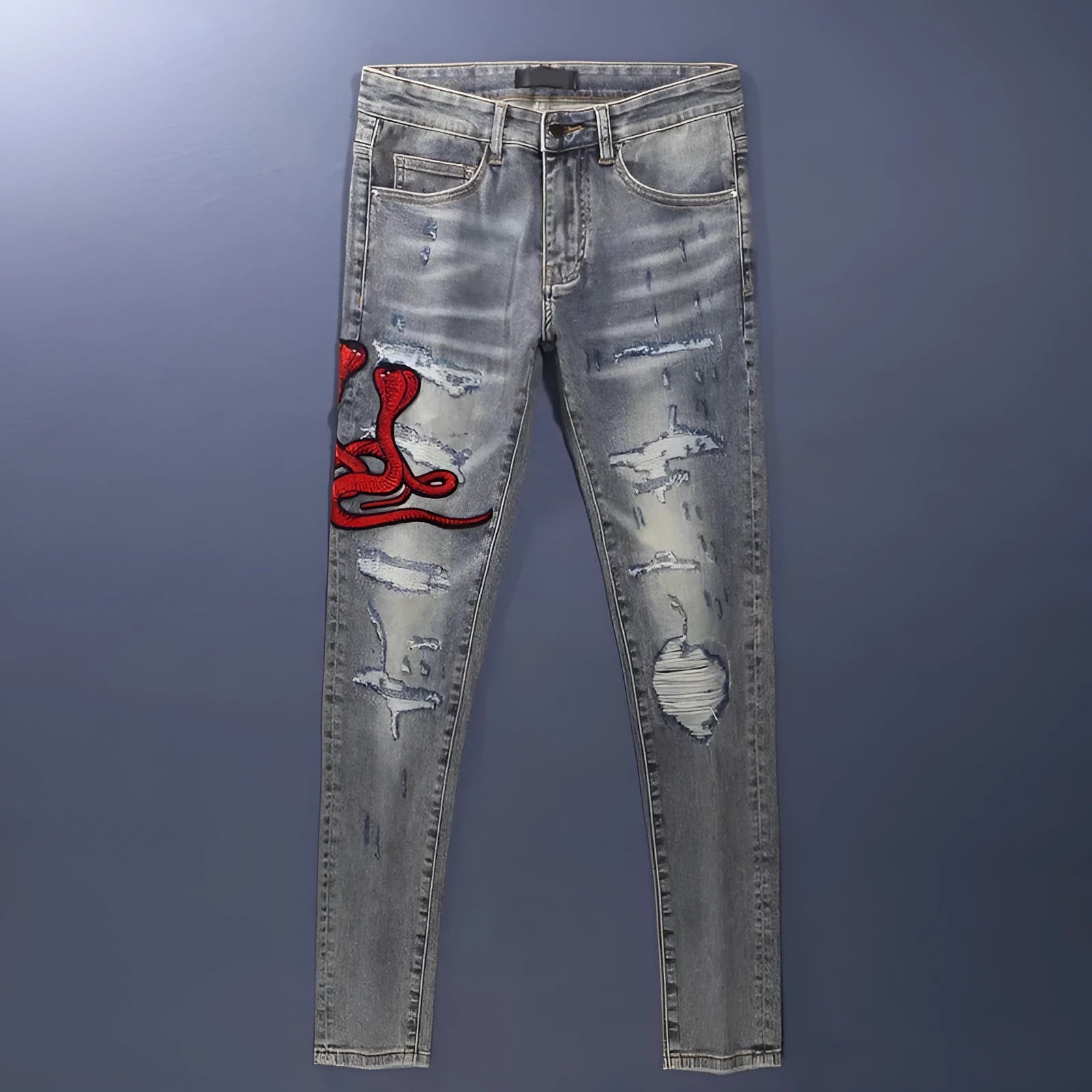 Slim fit light blue jeans with worn patches and embroidery on the legs, showing a washed-out colour.