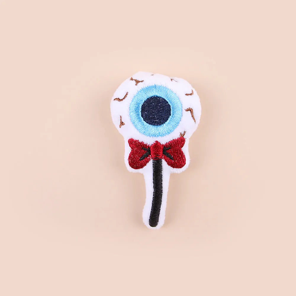 Small plush cat teaser wand toy showing candy, skull and eye patterns on soft fabric