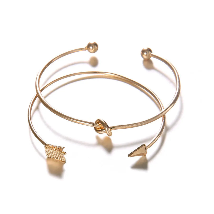 Gold electroplated alloy women's cuff bracelet with arrow and knotted design pattern