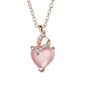 Women's pink heart crystal pendant necklace with rose gold cross chain on copper.