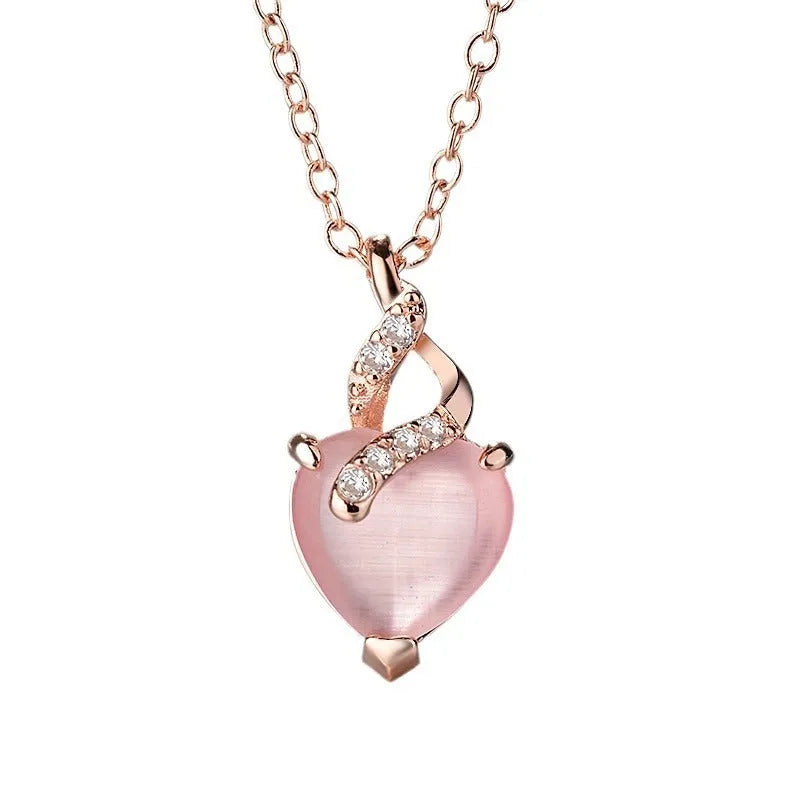 Women's pink heart crystal pendant necklace with rose gold cross chain on copper.