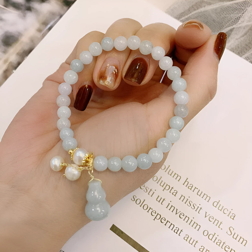 Close-up of a women's jade bracelet with a gourd motif, emerald jade insets, and pearl accents.