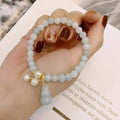 Close-up of a women's jade bracelet with a gourd motif, emerald jade insets, and pearl accents.