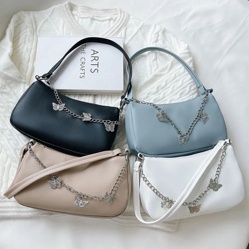 Women's butterfly chain underarm bag in black colour showing crossbody strap and three-dimensional pocket