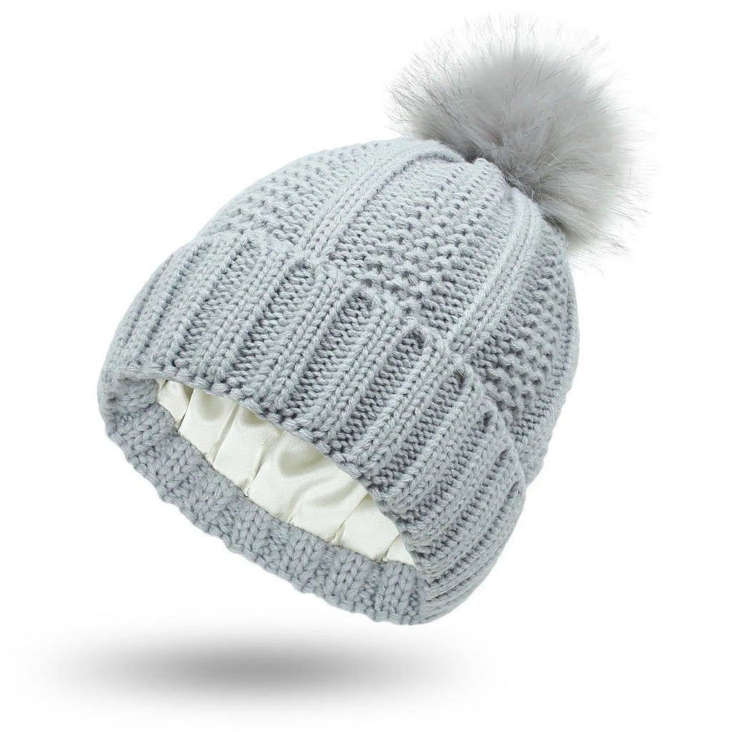 Women's knitted beanie hat with faux fur pom pom and satin lining in beige colour