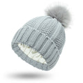 Women's knitted beanie hat with faux fur pom pom and satin lining in beige colour