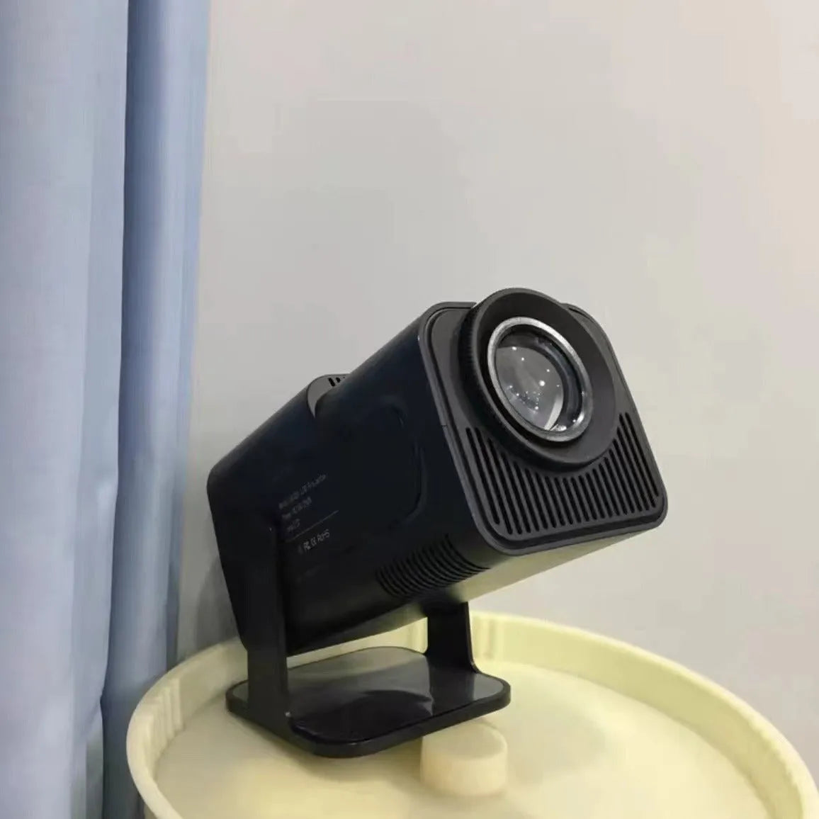 White home projector with carrying handle on a table, set up for wireless gaming projection.