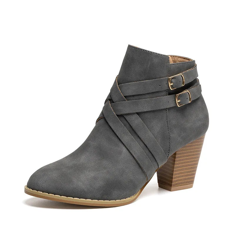 Grey PU leather short ankle boot with a 7cm chunky heel, side zip, and belt buckle on a wooden background.