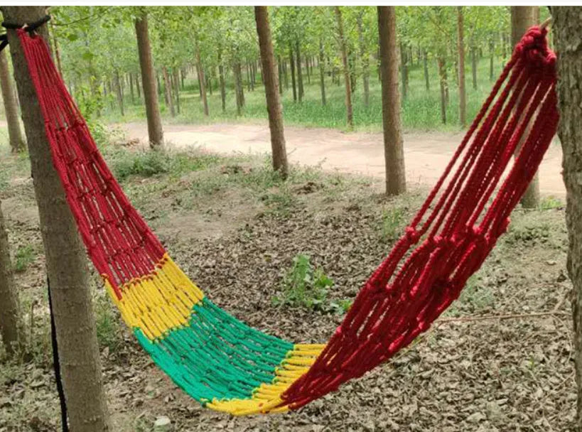 Outdoor nylon rope mesh hammock hung between two trees showing its woven construction and included tying ropes.