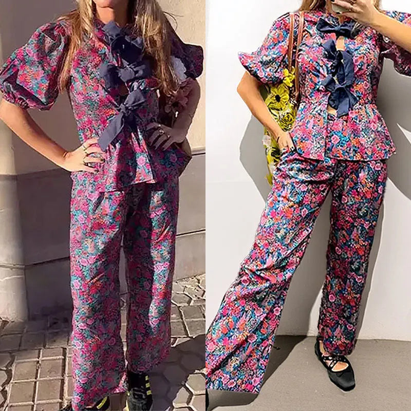 Women's floral print two-piece trouser suit with puff sleeve top and matching trousers.