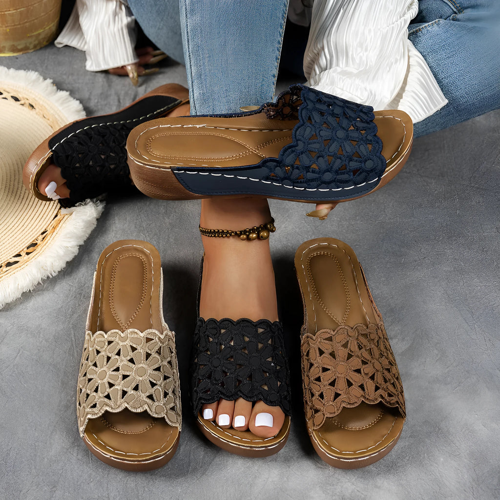 Women's wedge heel beach slippers with flower cutout design on black PVC upper.
