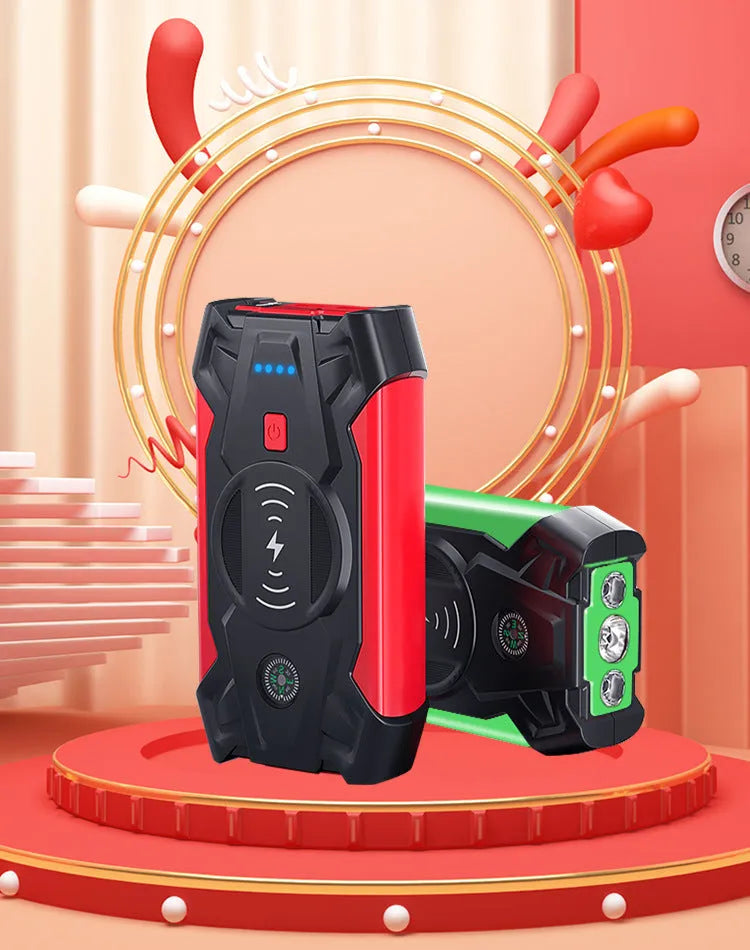 Red portable car jump starter and power bank unit with jumper cables on a table