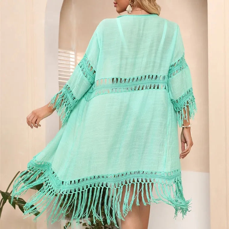 Yellow hand crocheted women's beach cover-up cardigan with tassels on a hanger