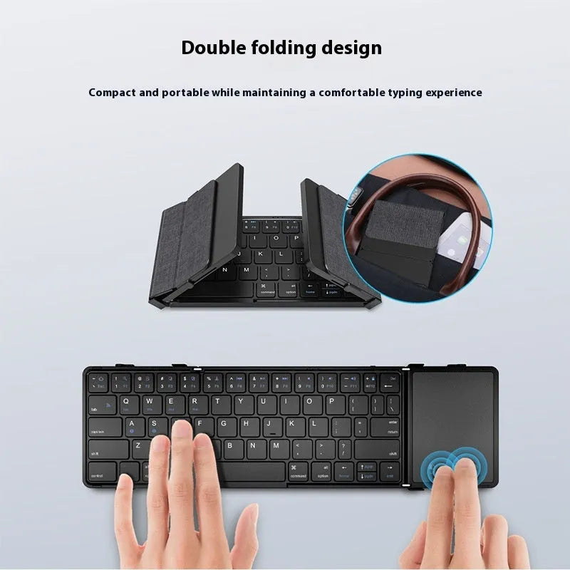 Black folding Bluetooth keyboard with touchpad unfolded next to mobile phone