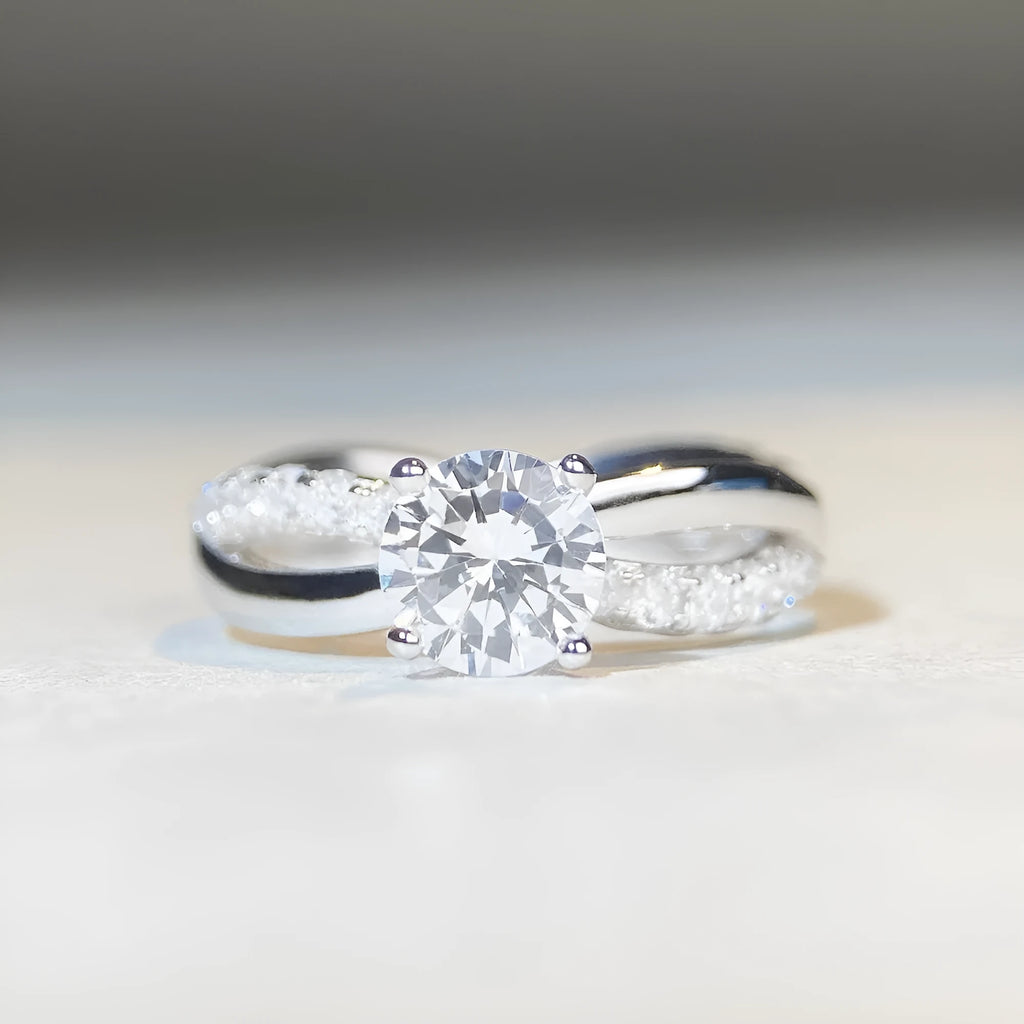 Geometric silver ring with twisted band and a 1 karat moissanite stone in a four-claw setting.