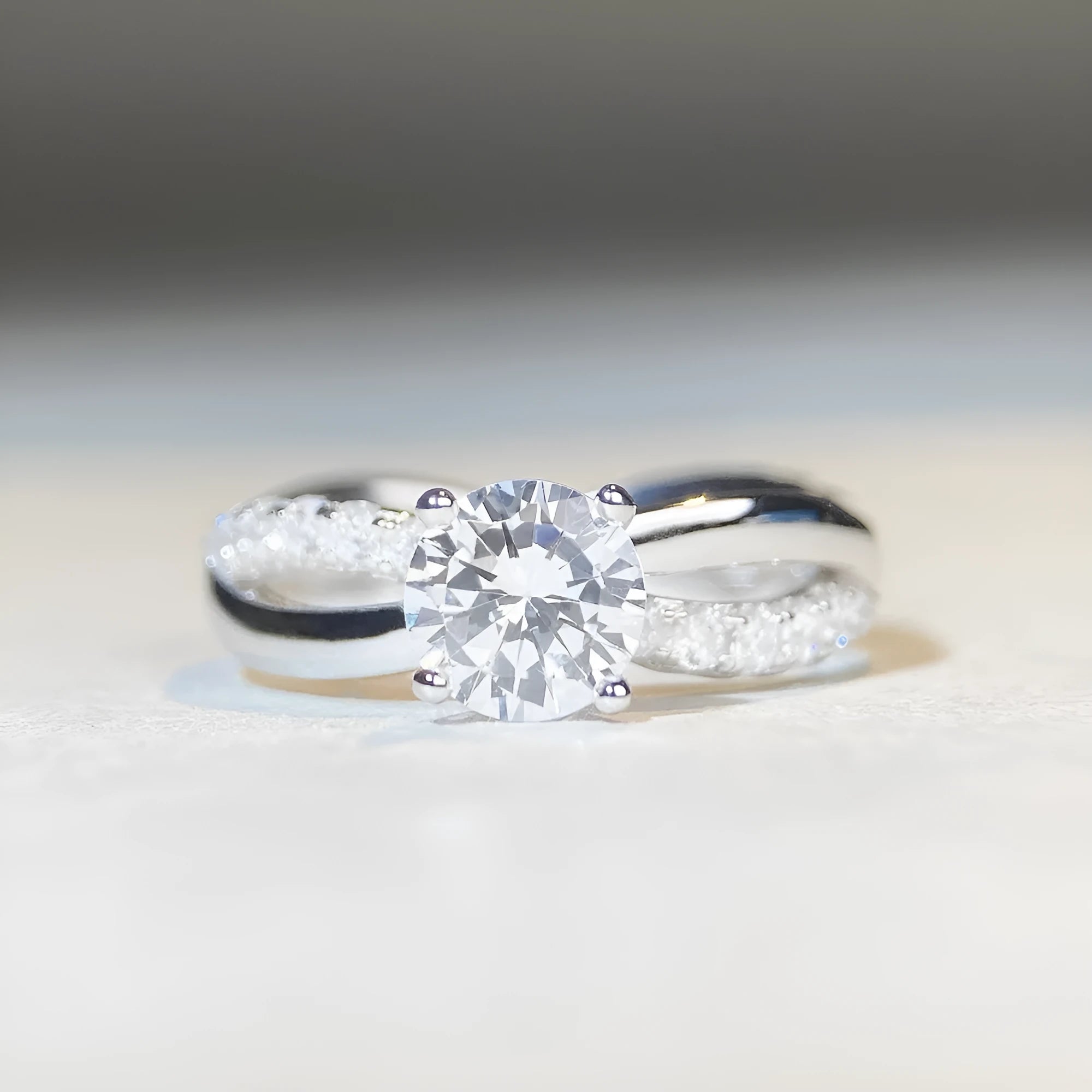 Geometric silver ring with twisted band and a 1 karat moissanite stone in a four-claw setting.