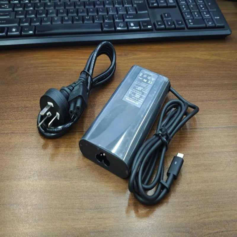 Black 65W Type-C laptop power adapter with multiple international plug heads on a white background.