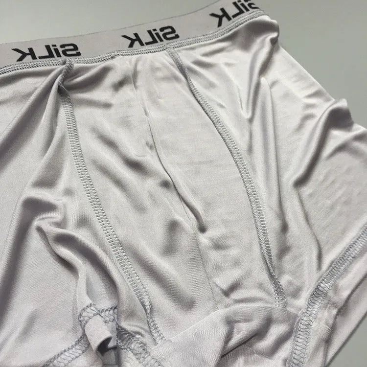 Man wearing loose-fitting mid-waist silk shorts in navy blue, silver grey, or skin colour.
