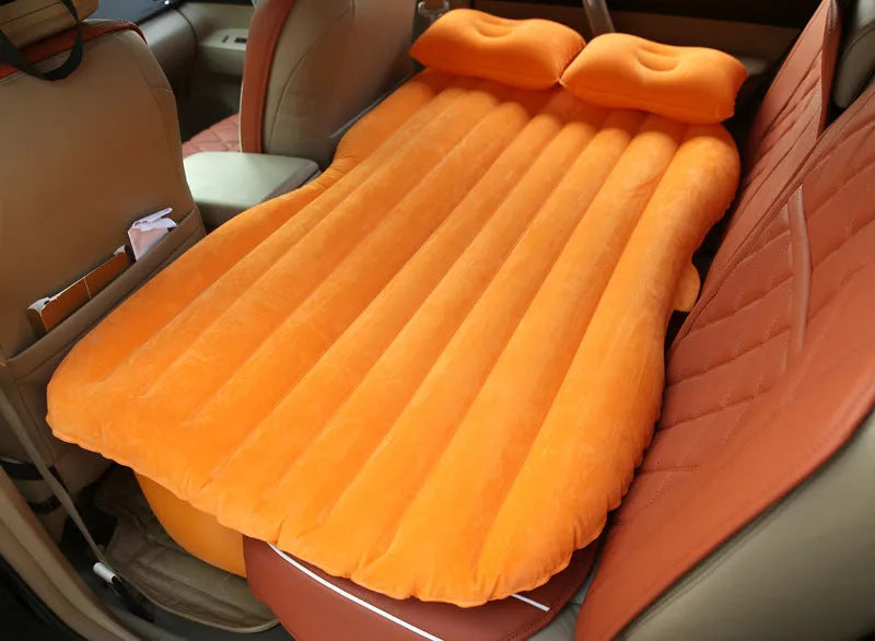 Black inflatable car bed with flocked texture and two pillows, shown inside a car boot.