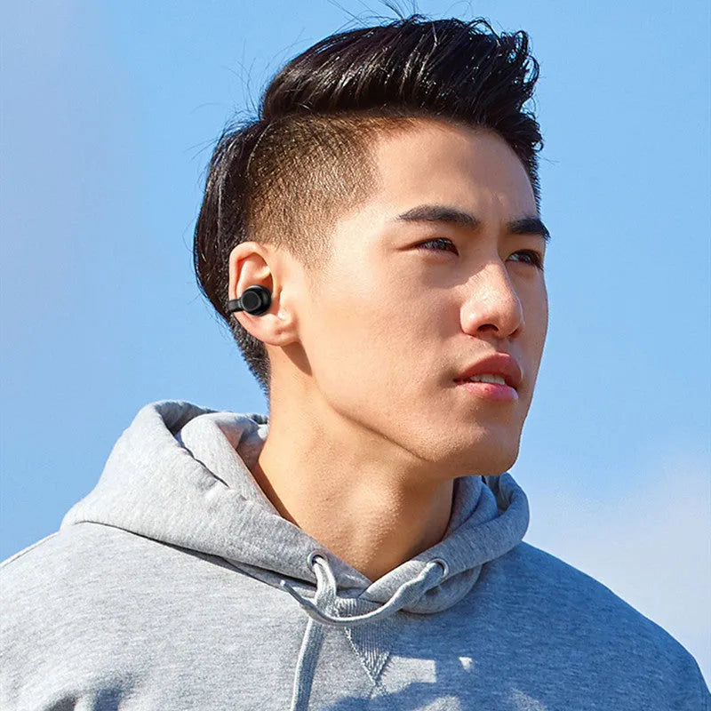 Black wireless bone conduction clip-on bluetooth earphones with charging cable on white background