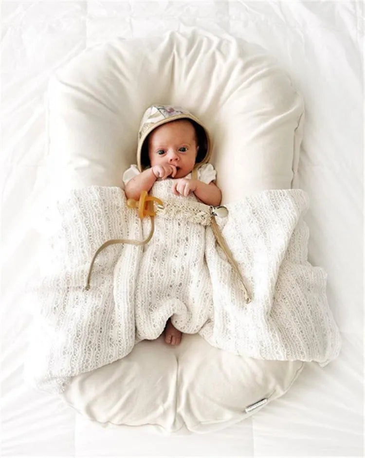 Beige portable baby nest crib cushion measuring 75cm by 45cm on a neutral background
