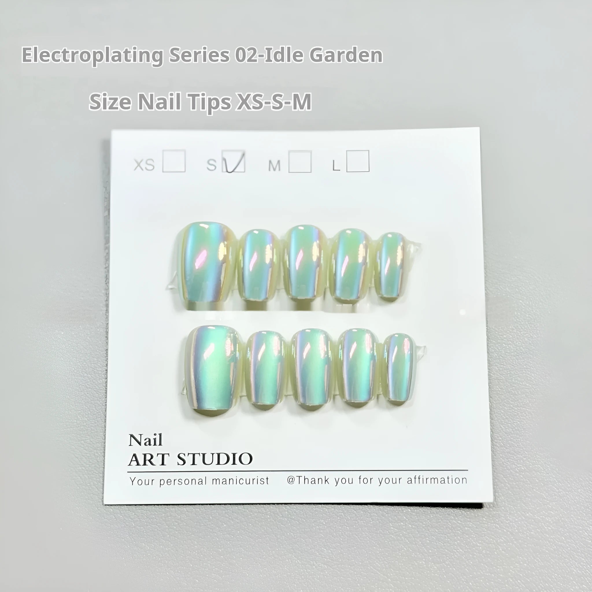 Set of electroplated Cat's Eye false nails with Aurora shine in short ladder sizes on a plain background.